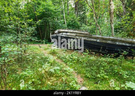 Altes verlassene hölzerne Fischerboot im Wald. Bootfriedhof in der Nähe der Ostsee in Lettland Stockfoto