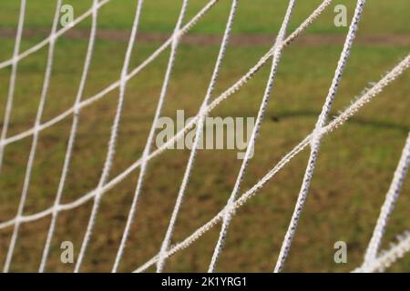 Das Gitter aus dem alten Fußballtor Nahaufnahme auf dem Hintergrund des Fußballfeldes. Stockfoto