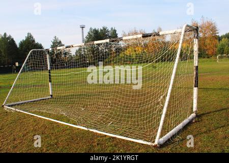 Altes Fußballtor vor dem Hintergrund des Fußballfeldes und des Herbstwaldes Stockfoto