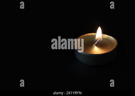 Brennende Kerze Nahaufnahme auf schwarzem Hintergrund mit Kopierraum. Stockfoto