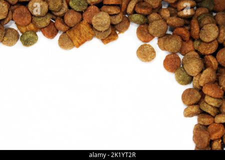 Trockenfutter für Katzen werden Hunde in Form eines Rahmens auf einem hellen Hintergrund mit einem Kopierraum ausgelegt. Nahaufnahme. Stockfoto