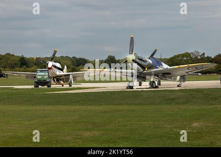 Spitfire- und Mustang-Kampfflugzeuge des Zweiten Weltkriegs auf dem Vorfeld eines Flugplatzes in Großbritannien Stockfoto