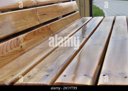 Leichte Holzbank im Stadtpark aus nächster Nähe. Stadtarchitektur. Stockfoto