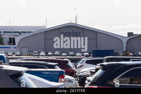 Am Toronto Island Airport ist ein Porter Airlines Hanger zu sehen, der an einem bewölkten Tag auf dem Flughafenparkplatz gegenüber geparkten Autos steht. Stockfoto