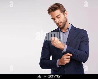 Das Erscheinungsbild aufrecht erhalten. Studioaufnahme eines gut gekleideten Mannes vor grauem Hintergrund. Stockfoto