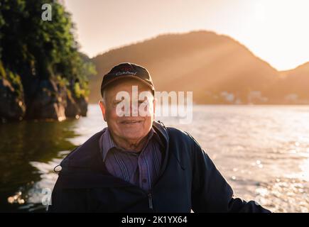 Porträt eines lächelnden älteren Mannes auf einem Boot bei Sonnenuntergang in Neufundland. Stockfoto