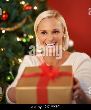 Das gehört dir. Eine fröhliche junge Frau, die ein Geschenk hält. Stockfoto