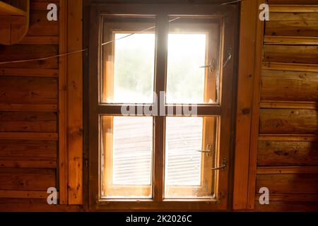 Ein Holzfenster in einer Wand aus Holzstämmen mit weißem Hintergrund. Stockfoto