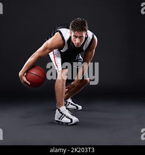 In Topform bleiben. In voller Länge Porträt eines männlichen Basketballspielers in Aktion vor einem schwarzen Hintergrund. Stockfoto