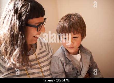 Es gibt nichts wie eine Mutterliebe. Ein kleiner Junge, der mit seiner Mutter sitzt. Stockfoto