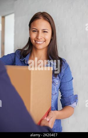 Als sie die letzte Schachtel empfing... Lächelte eine schöne junge Frau an der Kamera, als sie eine Schachtel von einem Mover nahm. Stockfoto