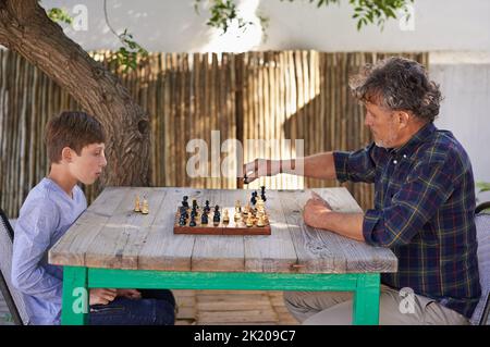 Schach spielen mit seinem Großvater. Ein kleiner Junge spielt Schach mit seinem Großvater. Stockfoto