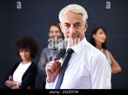 Mit meinem Team an die Spitze. Ein reifer professioneller Mann, der vor einer Gruppe von Mitarbeitern steht. Stockfoto