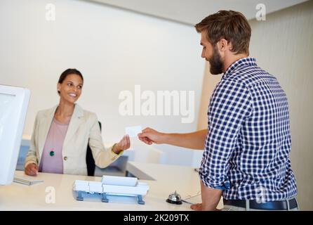 Hier ist Ihre Schlüsselkarte. Ein hübscher junger Mann, der in ein Hotel eincheckt. Stockfoto