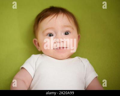 Shes ein entzückendes Freudenbündel. Ein entzückendes Baby Mädchen mit roten Haaren. Stockfoto