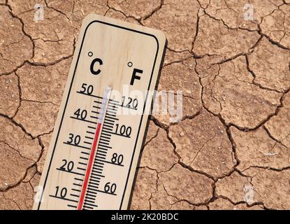 Holzthermometer zeigt heiße Temperatur auf getrockneter brauner Erdstruktur an Stockfoto