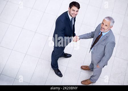 Gemeinsam haben wir etwas Besseres gebaut. Hochwinkelporträt von zwei Geschäftsleuten, die die Hände schütteln. Stockfoto