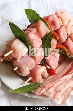 Spieße mit rohem Fleisch und Speck isoliert auf weißem Hintergrund. Stockfoto