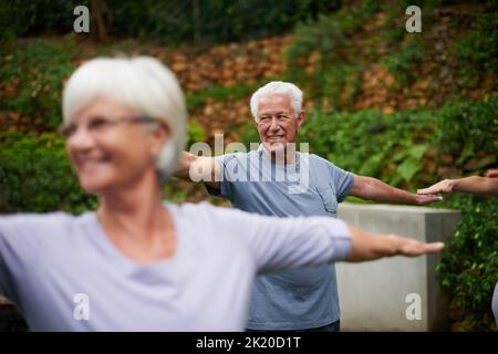 Ein älterer Mann, der einen Yoga-Kurs im Freien genießt. Stockfoto