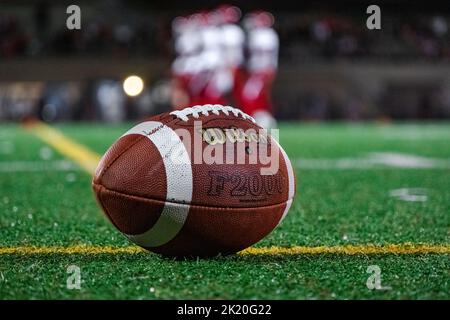 Nahaufnahme eines Wilson Fußballs auf Kunstrasen während eines Nachtfußballspiels mit Spielern im Hintergrund. Stockfoto