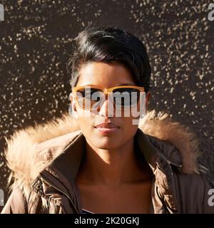 Königin im Straßenstil. Eine attraktive junge Frau, die sich an einer Wand lehnt. Stockfoto