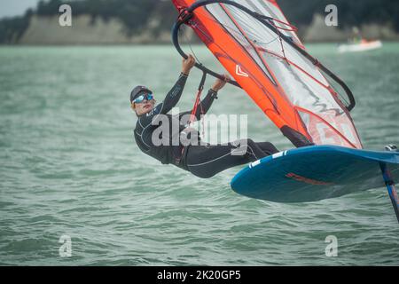 Ein Mann nimmt an einem nationalen Windsurf-Hydrofoil-Rennen beim Waterbourne Watersports Festival, Takapuna Beach, Auckland, Neuseeland, Teil. Stockfoto