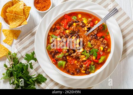 taco-Suppe aus Hackfleisch, Tomaten, gehackten grünen Chilis, Zwiebeln, Mais, Rote Bohnen und Taco-Würze in einer weißen Schüssel Stockfoto