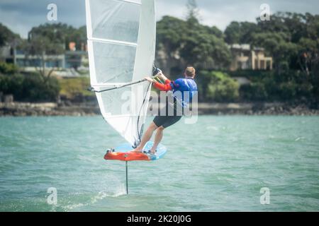 Ein Mann nimmt an einem nationalen Windsurf-Hydrofoil-Rennen beim Waterbourne Watersports Festival, Takapuna Beach, Auckland, Neuseeland, Teil. Stockfoto