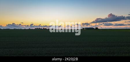 Panoramablick auf Wolken über die landwirtschaftliche Landschaft nach Sonnenuntergang. Stockfoto
