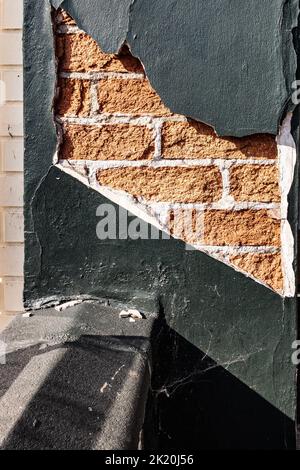 Alte abblätternde Gipsarbeiten, die die roten Ziegelwände dahinter freilegen. Nützlich für Hintergründe. Stockfoto