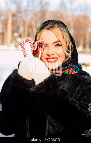 Eine junge schöne Frau in einem nationalen slawischen Kopftuch mit Lutschern Stockfoto