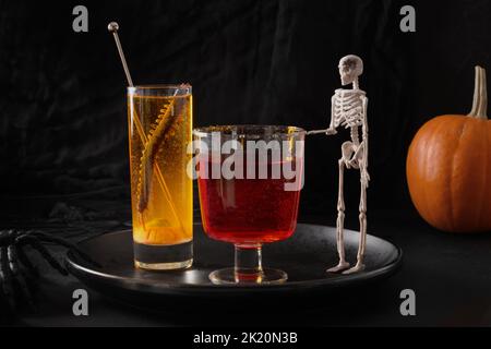 Halloween rote und orange alkoholische Cocktails auf schwarzem Hintergrund. Getränk für eine festliche Party. Stockfoto