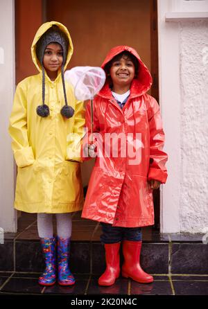 Sie sind Geschwister und beste Freunde. Porträt von zwei Kindern in Regenmänteln und Wellingtons. Stockfoto