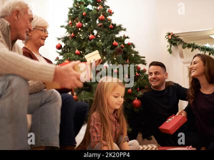 Erfüllt von der Freude des Schenkens. Eine Familie mit mehreren Generationen tauscht zu Weihnachten Geschenke aus. Stockfoto