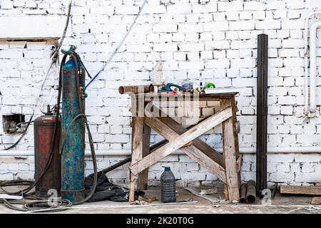 Alte Gasflaschen zum Schweißen und Schneiden. Rostige Propan- und Sauerstofftanks. Werkzeuge für die metallverarbeitende Industrie. Verlassene Baustelle. Stockfoto