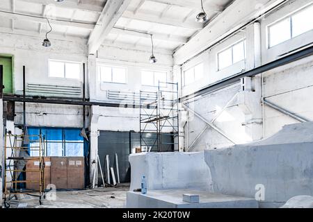 Bau einer Arbeitswerkstatt im Werk. Reparatur des Arbeitsraums. Gerüste, Leitern und Arbeitswerkzeuge. Stockfoto