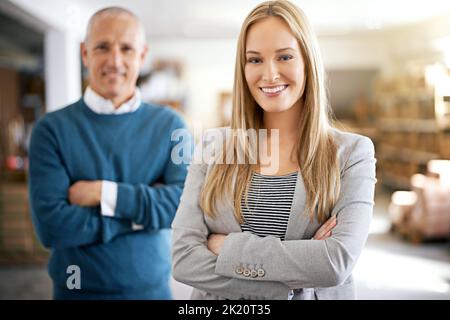 Seien Sie versichert, dass Ihre Sendung in guten Händen ist. Porträt zweier Manager, die in einem Lagerhaus stehen. Stockfoto