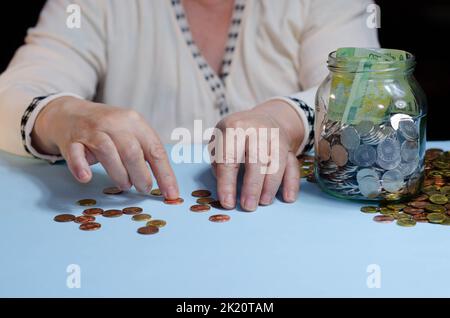 Ältere Frau, die Münzen auf dem Tisch zählt. Nahaufnahme der Makrodetails der rumänischen lei-Banknoten Stockfoto