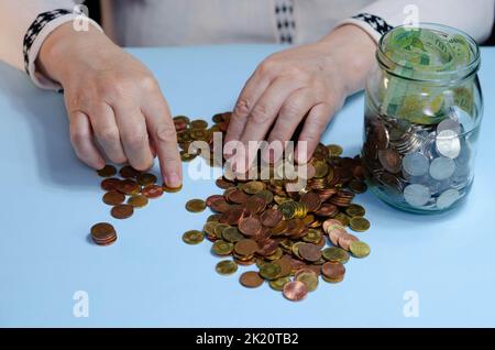 Ältere Frau, die Münzen auf dem Tisch zählt. Nahaufnahme der Makrodetails der rumänischen lei-Banknoten Stockfoto