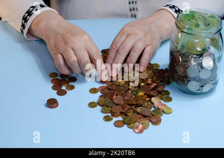 Ältere Frau, die Münzen auf dem Tisch zählt. Nahaufnahme der Makrodetails der rumänischen lei-Banknoten Stockfoto
