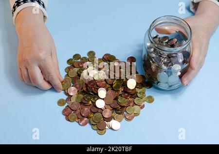 Ältere Frau, die Münzen auf dem Tisch zählt. Nahaufnahme der Makrodetails der rumänischen lei-Banknoten Stockfoto