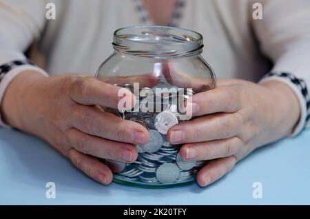 Ältere Frau, die Münzen auf dem Tisch zählt. Nahaufnahme der Makrodetails der rumänischen lei-Banknoten Stockfoto