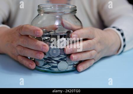 Ältere Frau, die Münzen auf dem Tisch zählt. Nahaufnahme der Makrodetails der rumänischen lei-Banknoten Stockfoto