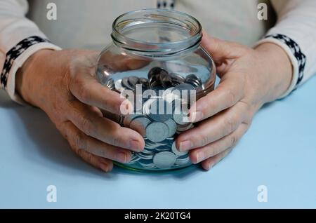 Ältere Frau, die Münzen auf dem Tisch zählt. Nahaufnahme der Makrodetails der rumänischen lei-Banknoten Stockfoto