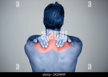 Die Schmerzen und Schmerzen spüren. Rückansicht eines Studios, in dem ein reifer Mann die hervorgehobene Verletzung an seinem Körper reibt. Stockfoto