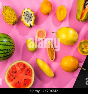 Vielfalt tropischer Früchte auf fuchsiafarbenen und schwarzen Hintergrund Stockfoto