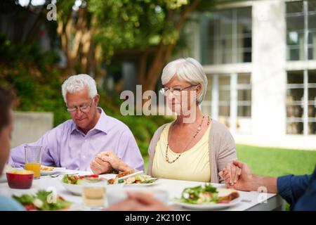 Dankbar für das, was wir erhalten werden. Eine Familie, die gemeinsam Gnade sagt. Stockfoto