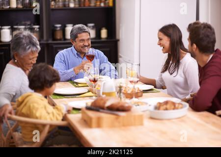 Cheers an die beste Familie. Eine Aufnahme einer glücklichen Familie, die zusammen eine Mahlzeit teilt. Stockfoto