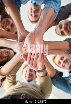 Teamarbeit erledigt die Arbeit. Aufnahme einer Gruppe von Mitarbeitern, die ihre Hände übereinander stapeln. Stockfoto