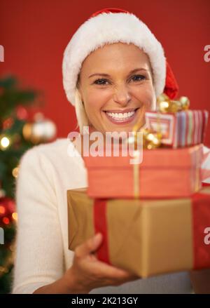 Die Geschenke stapeln sich. Eine glückliche junge Frau hält einen Stapel weihnachtsgeschenke in der Hand. Stockfoto